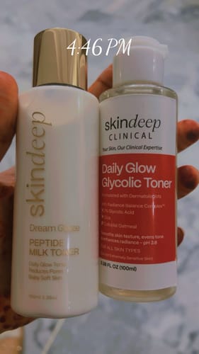 A reviewer holds the white bottle of DREAM GLAZE - Peptide Milk Toner next to another Skindeep toner.