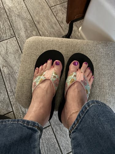 Reviewer's top-down view of the Rosy Retreat flip flops, showing the delicate floral print on the straps.