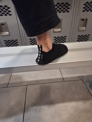 Reviewer wearing the black Touch IV shoes while standing on a bench in a locker room.