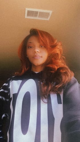 Customer showing their reddish wig styled with soft curls.