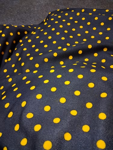Customer's close-up of the soft black polyester jersey fabric with a vibrant yellow polka dot print.