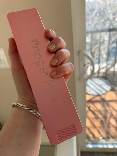 Reviewer holding the pink metal Weekly Case, highlighting their matching glittery nail polish.