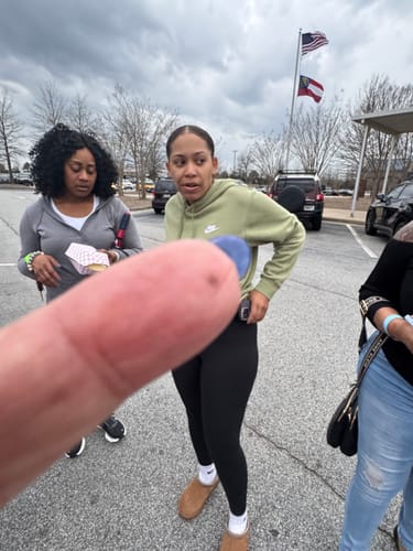 Reviewer's photo of three people in a parking lot, with the foreground obstructed by a finger.