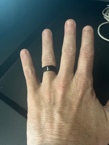 Reviewer's hand showing the black Silicone Wedding Ring with its stainless steel strip.
