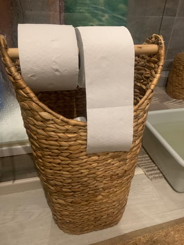 Client montrant deux rouleaux de papier toilette compact sur un support en osier.