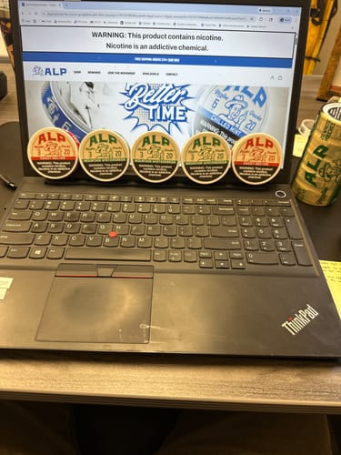 Reviewer's cans of ALP Mountain Wintergreen and another flavor of nicotine pouches on a laptop.
