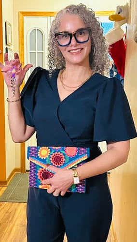 Customer smiling, wearing the shiny, gold Chunky Hoop earrings with a dark blue outfit and necklace.