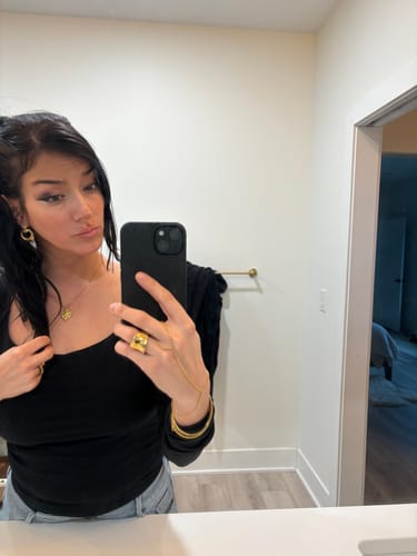 Reviewer taking a mirror selfie while wearing the gold Rome Pendant layered with other jewelry from the bundle.