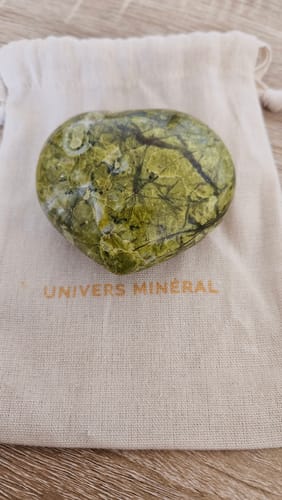 Photo d'un client du Coeur en Opale Verte, une pierre verte polie, posée sur son pochon.