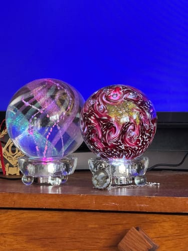 Customer's two Lucite Light Stands illuminating decorative glass globes placed side-by-side on a shelf.