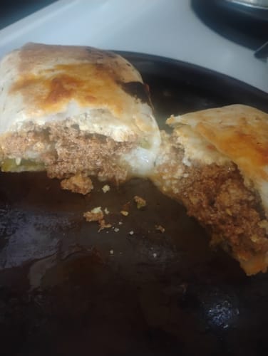 Close-up of a customer's Bangin' Breakfast Burrito cut in half, showing the dense ground turkey filling.