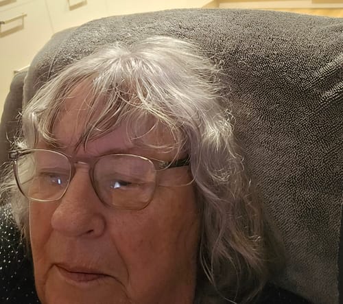 Reviewer using a grey KoalaCloth as a head protector on a lounge chair.
