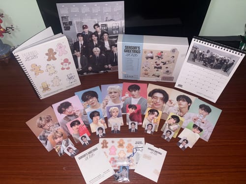 Reviewer's ATEEZ 2026 Season's Greetings set unpacked, showing the planner, calendars, box, and multiple photocards.