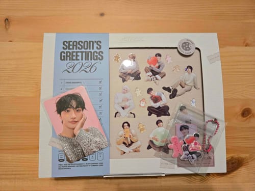Customer's ATEEZ 2026 Season's Greetings box with a photocard and other gift inclusions displayed on a wooden table.