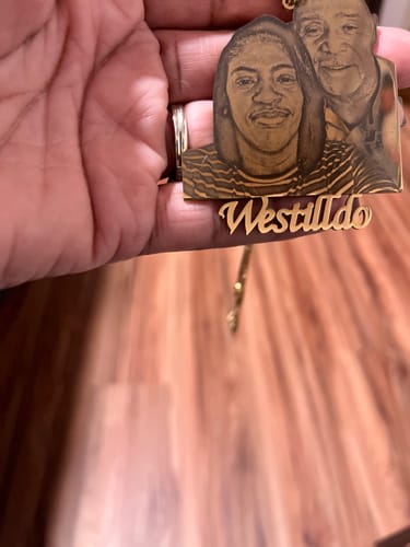 Customer holding their gold-colored Custom Photo Engraved Pendant with an image of two people and custom text.