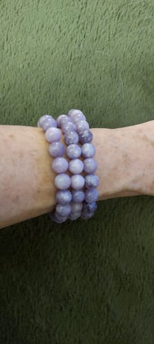 Une cliente portant trois bracelets Lépidolite de perles violettes à son poignet.