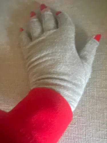 Customer's hand wearing a grey, fingerless Onecompress™ Glove with a red sleeve at the wrist, resting on a surface.
