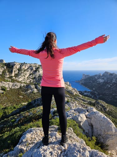 Rückansicht einer Kundin in einer schwarzen Tofana Leggings auf einem Felsen mit Blick auf das Meer.