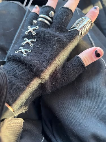 Reviewer's hand wearing the silver RIBCAGE RING on their index finger with a black fingerless glove.