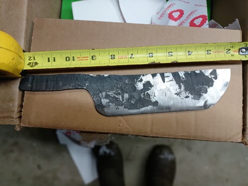 A customer measures a rough-forged knife blank, a project being worked on with the ceramic grinding belts.
