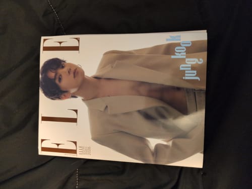 Customer's ELLE magazine featuring Jung Kook on the cover, resting on a dark, quilted surface.