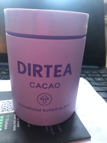 Customer's purple canister of DIRTEA Cacao sitting on a desk in front of a laptop.