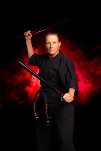 A reviewer for Meraki Blu Methylene Blue pictured in a martial arts uniform holding batons.
