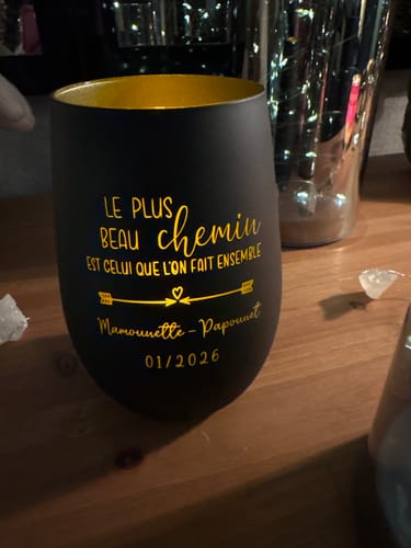 Photo d'un client montrant un gobelet noir personnalisé avec une inscription dorée.