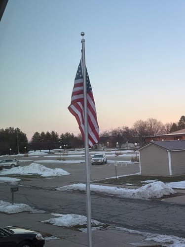 Customer's American Nylon Flag hanging on a flagpole in a snowy lot at dusk.