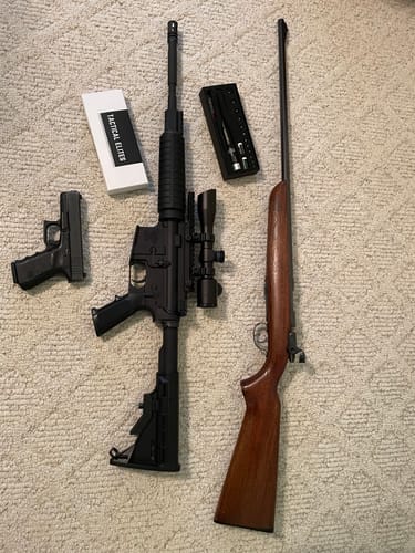 Customer's Site Right Boresighter kit and packaging laid out with a pistol and two rifles on a carpet.