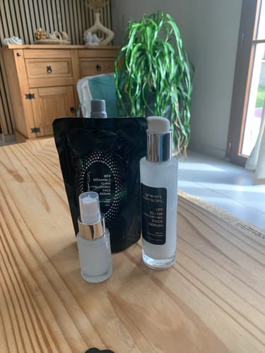 Cliente présentant deux flacons de sérum et une recharge noire sur une table en bois.