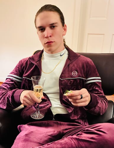 Customer relaxing in the Potent Purple Bandiera Track Pant and matching velour track jacket.