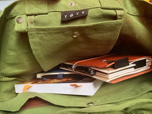 Close-up of a customer's Khaki Green TØTE Bag, showing the spacious interior holding several notebooks.