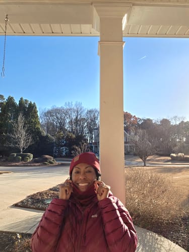 Reviewer smiling outdoors, wearing the Rhubarb Neck Gaiter pulled up to their chin for warmth.