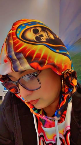 Close-up of a customer wearing the colorful Chingona Art Hoodie with the hood pulled up.