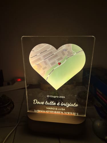 Rezensent zeigt die beleuchtete, personalisierte Acryl-Plakette mit einer herzförmigen Karte, die in einem dunklen Raum leuchtet.