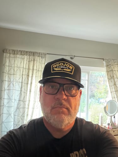 Customer wearing the black Big Military Hat with a gold logo patch indoors.