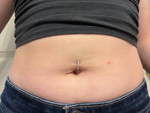 A customer's torso showing the Implant Grade Titanium Paved Luxe Hinged Belly Clicker worn in their navel.
