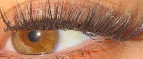 Kundin zeigt in einer Nahaufnahme ihres Auges die langen, natürlichen THE LEO Wimpern.