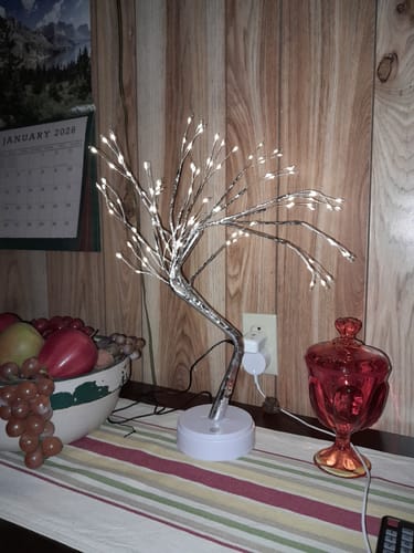 Customer's Fairy Light Spirit Tree, brightly lit and placed on a striped table runner next to a fruit bowl.