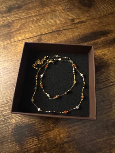 Reviewer's gold Lulu Beaded Stone Necklace with colorful beads displayed in a jewelry box.