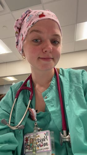 Reviewer in green scrubs wearing the pink 'Winter Snoopy' DuoStyle Scrub Hat and a stethoscope.