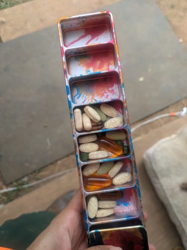 Reviewer holding the open Weekly Case, showing its colorful interior and compartments filled with various vitamins.