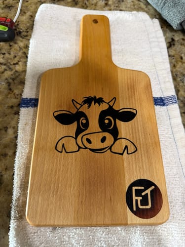 Customer's wooden cutting board with a neatly burned-in cartoon cow design created using the Intermediate Bundle.