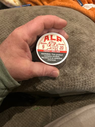 Customer holding a round, white can of ALP Sweet Nectar Nicotine Pouches.