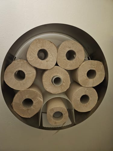 Client montrant ses rouleaux de papier toilette Beau et Doux rangés dans un distributeur mural.