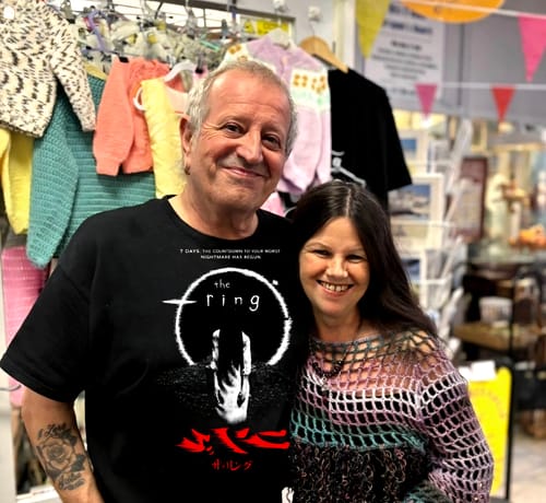 Customer wearing a black unisex t-shirt with "The Ring" graphic, smiling with another person.