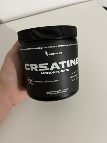 Customer holding a black tub of Complex Creapure Creatine Monohydrate.