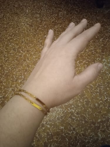 Customer showing two lovely gold Aurora bracelets stacked on their wrist against a brown speckled floor.