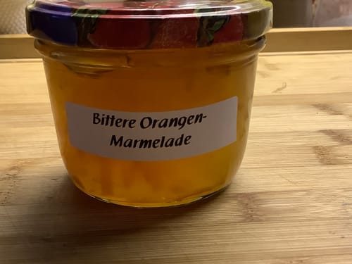 Ein Glas hausgemachte Bitterorangen-Marmelade des Kunden auf einem Holztisch.